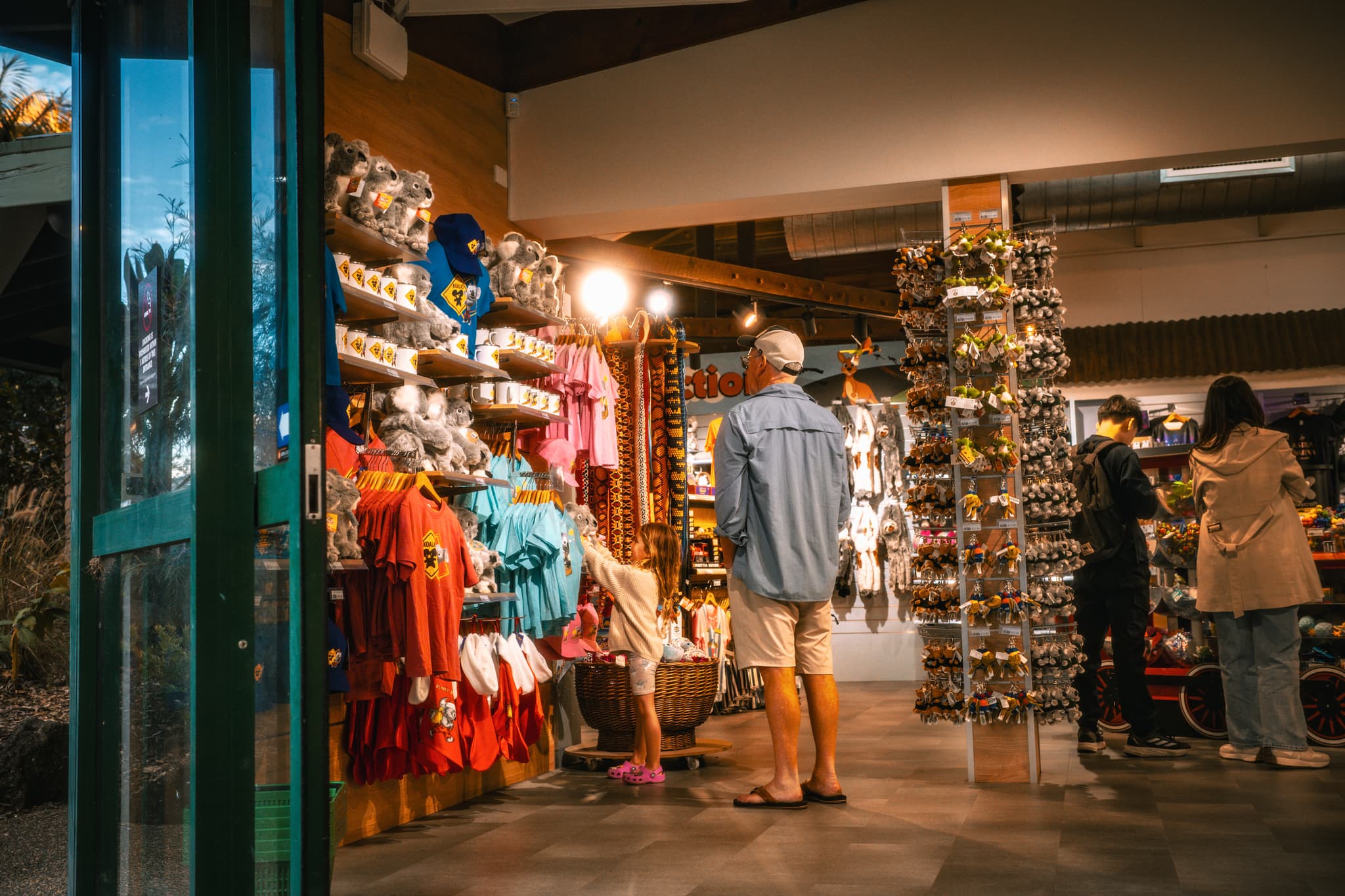 Interior of a souvenir shop with postcard racks, clothing displays, and shoppers browsing near the entrance
