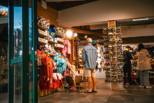 Interior of a souvenir shop with postcard racks, clothing displays, and shoppers browsing near the entrance