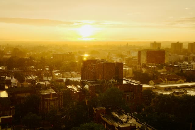 Sunrise over an urban skyline with low buildings and a hazy golden horizon