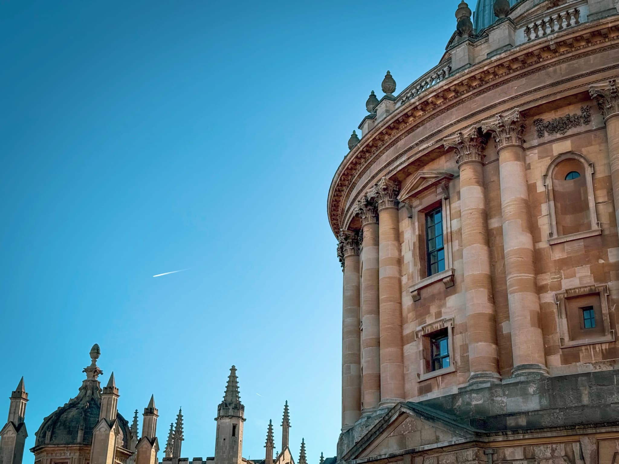 A historic building with a domed structure and ornate architecture under a clear blue sky, accompanied by spires in the background