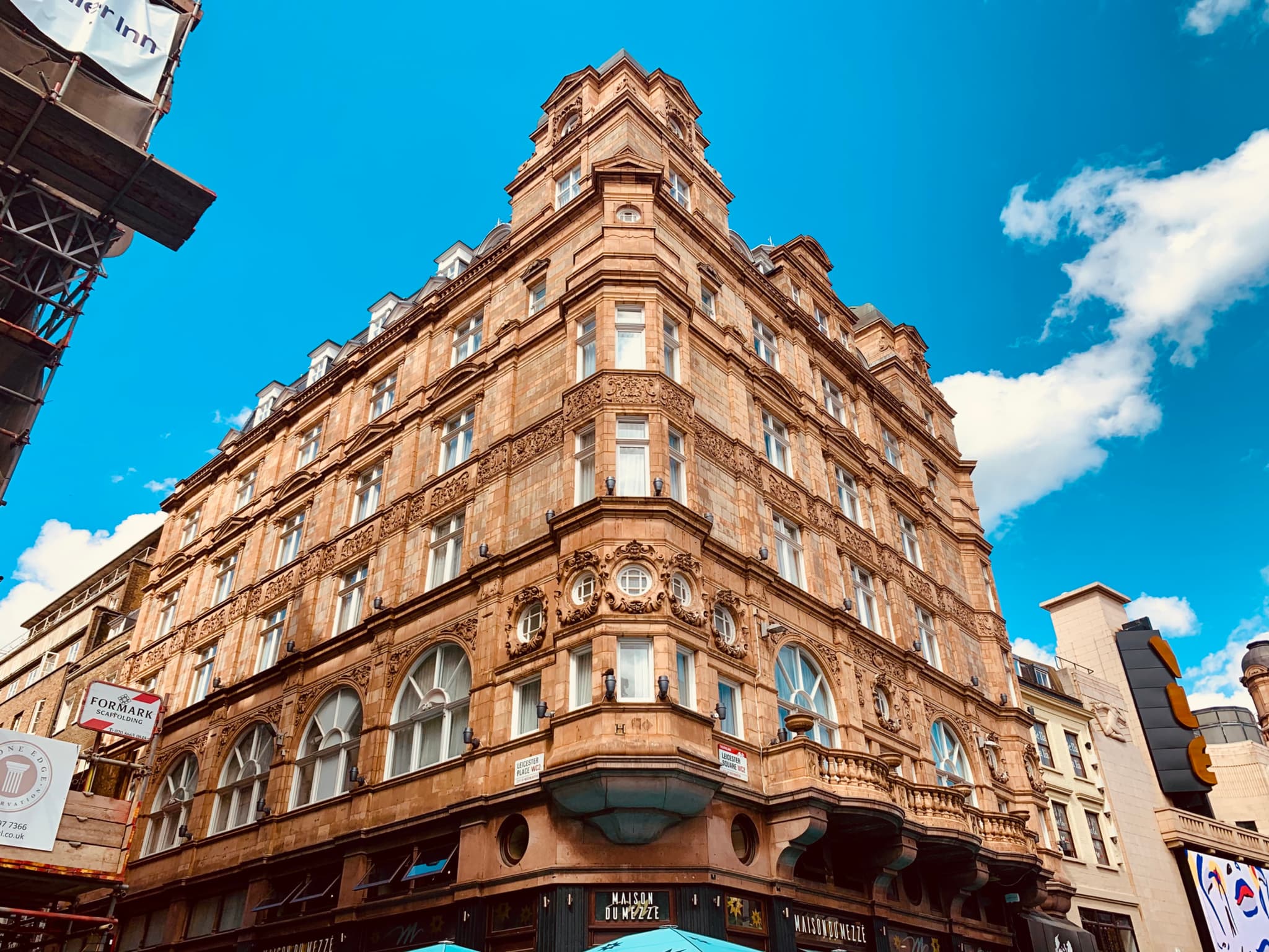 A historic, ornate corner building with intricate architectural details under a bright blue sky