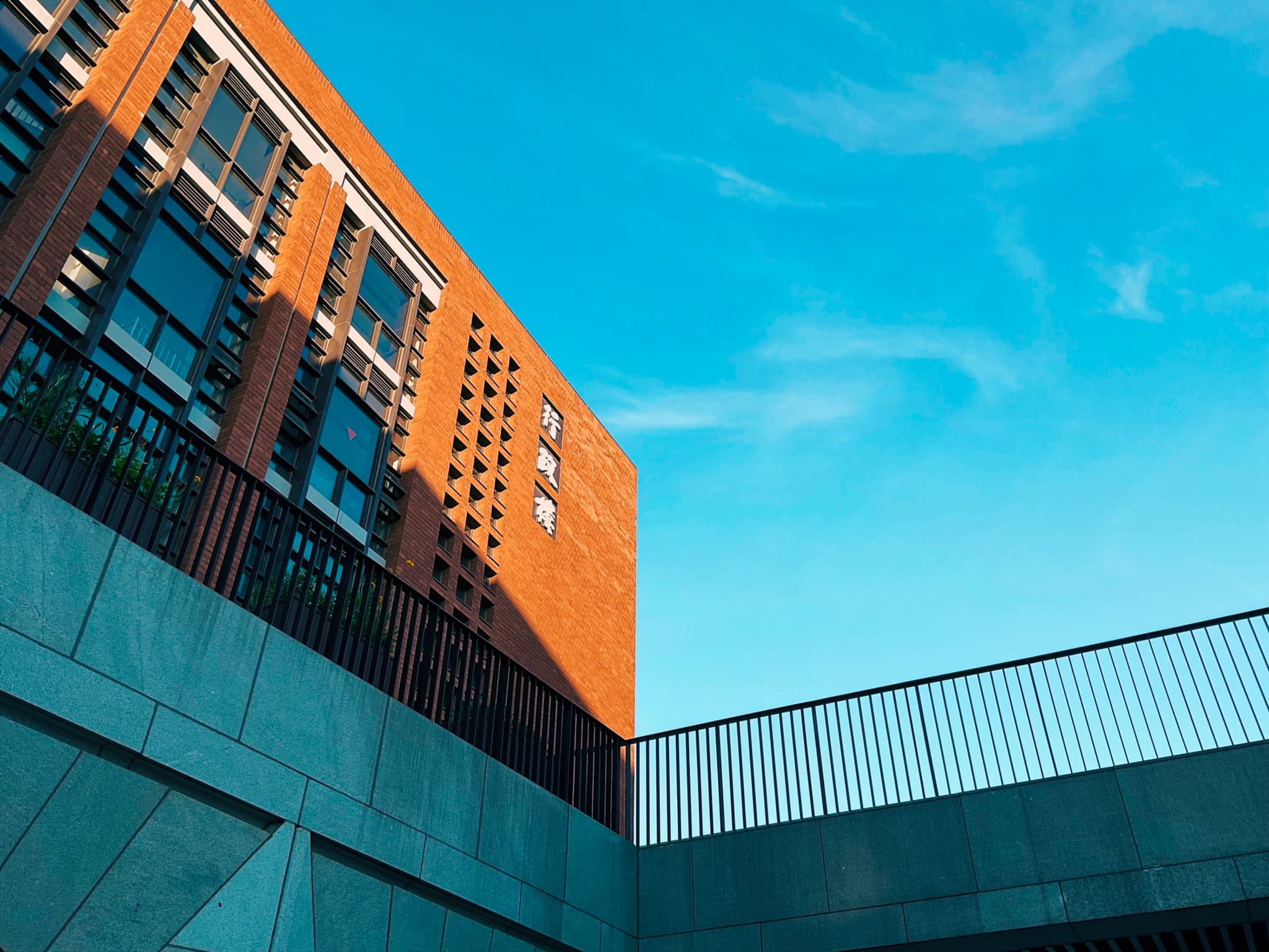 A modern NFLS School administration building with a geometric design against a clear blue sky